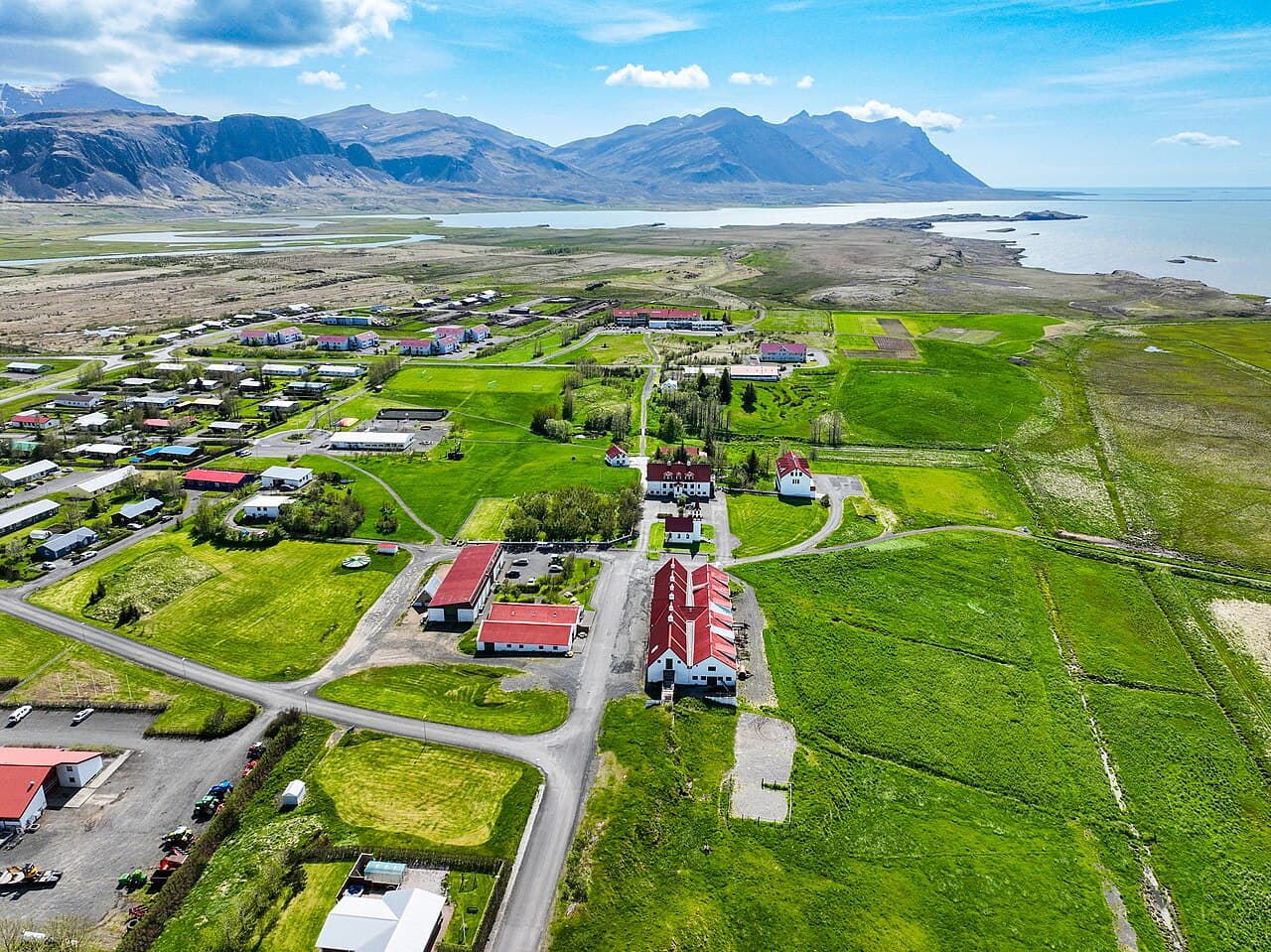 Aerial view of Hvanneyri with red-roofed university buildings, green fields and a fjord with mountains