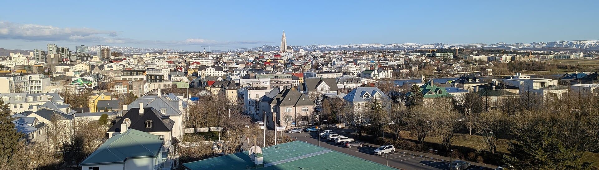 Panorama of Reykjavík with Hallgrímskirkja and snow-capped mountains under a blue sky