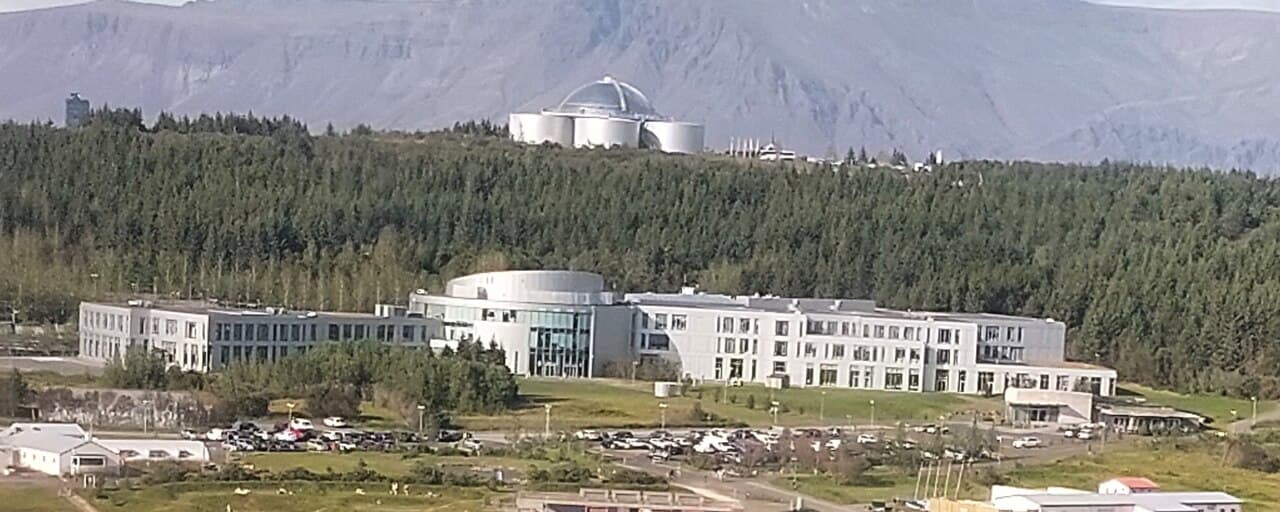 Aerial view of the Reykjavík University building at Nauthólsvík, with Perlan on the wooded hill behind