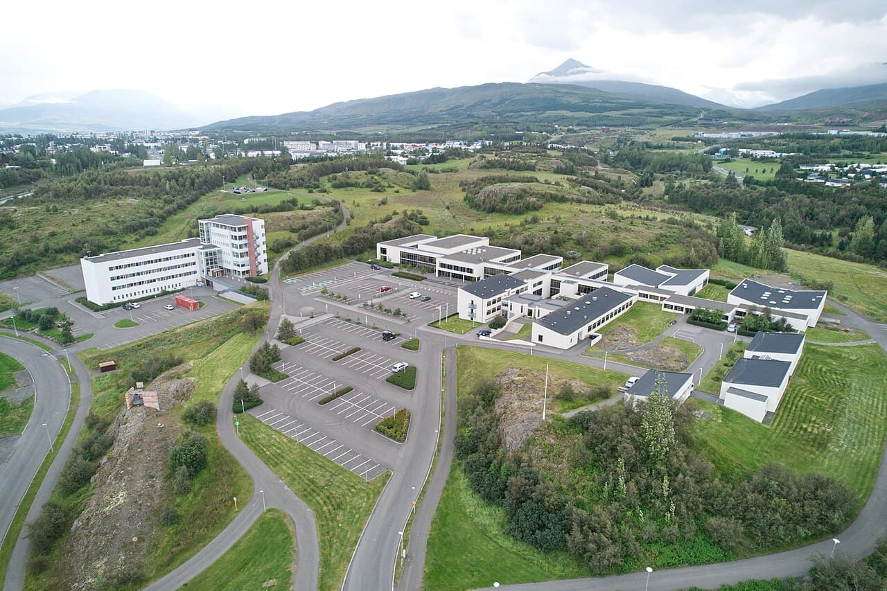 Aerial view of the University of Akureyri campus with green hills and mountains behind